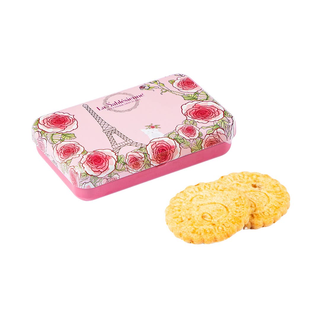 Pink cookie tin with floral design and two cookies on a white background