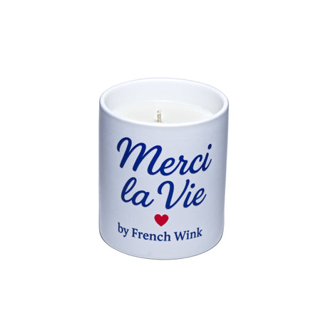 White candle with 'Merci la Vie' text and a red heart on a light gray background