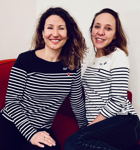 Two women wearing navy and white Breton striped marinière shirts