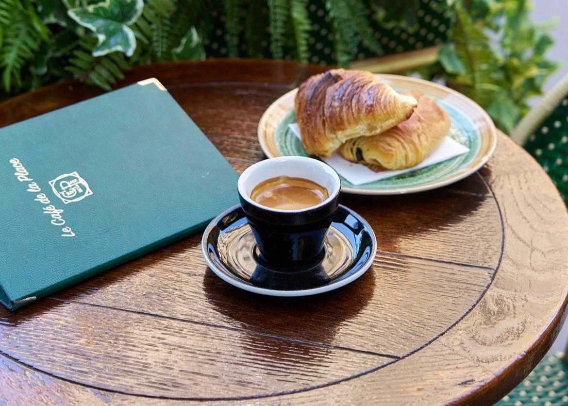 French café table with an espresso, croissant, and menu