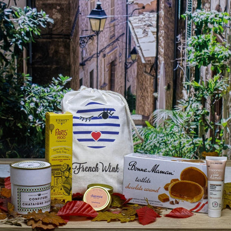 Collection of French products including a candle, cookies, and a bag with a Fall scenic background.