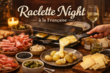 Raclette night setup with raclette grill, cheese, and various foods on a table.