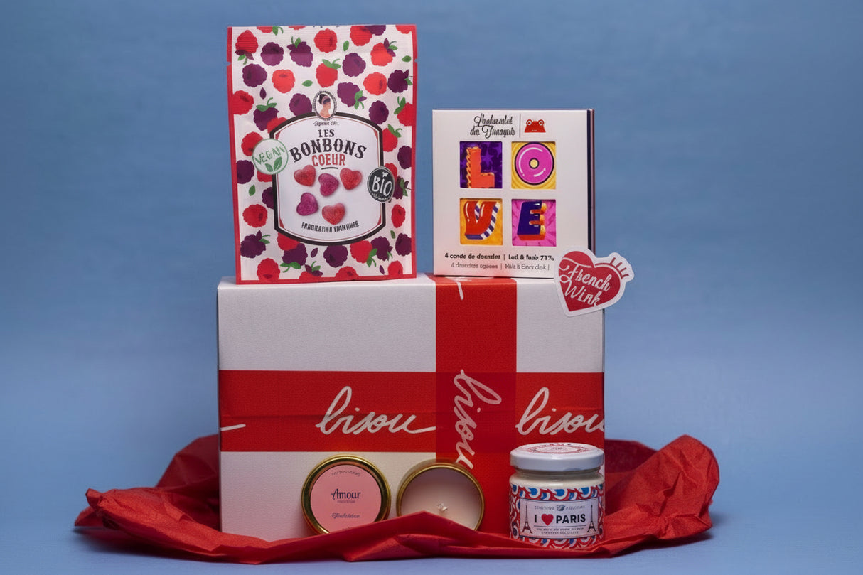 A gift set including various romantic-themed French products such as chocolates, a candle, and spreads, all presented in a white box with red accents and labeled with 'Amour' and 'bisou'.