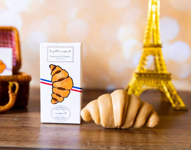 Croissant-shaped cookie with packaging and Eiffel Tower model in the background