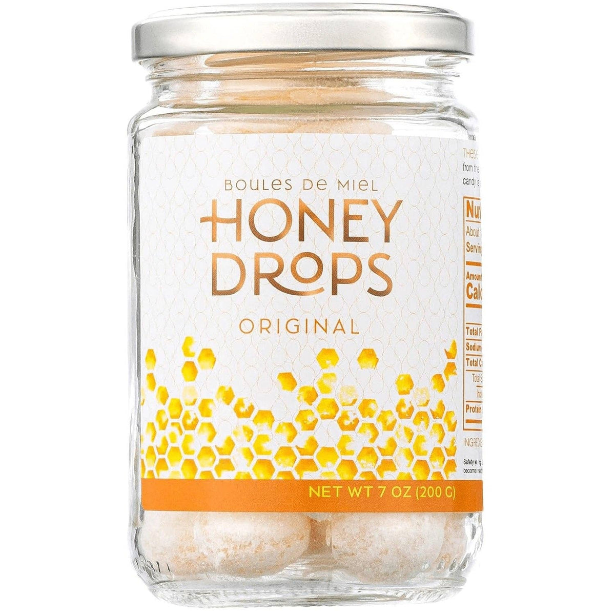 A 7 oz glass jar of Honey Drops Original honeycomb candies, featuring a white label with gold lettering and a honeycomb pattern, sealed with a silver metal lid on a white background.