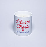 White candle with red text 'Liberté Chérie' and a heart symbol, branded by French Wink on a light gray background.
