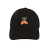 A black baseball cap featuring an embroidered white cursive word 'oui' and a small orange croissant graphic on the front, set against a plain white background.