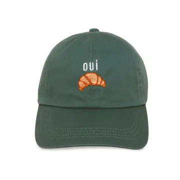 A green baseball cap with 'OUI CROISSANT' embroidered on the front.