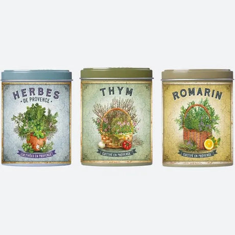 Three tin cans labeled 'Herbes de Provence', 'Thym', and 'Romarin' on a white background.