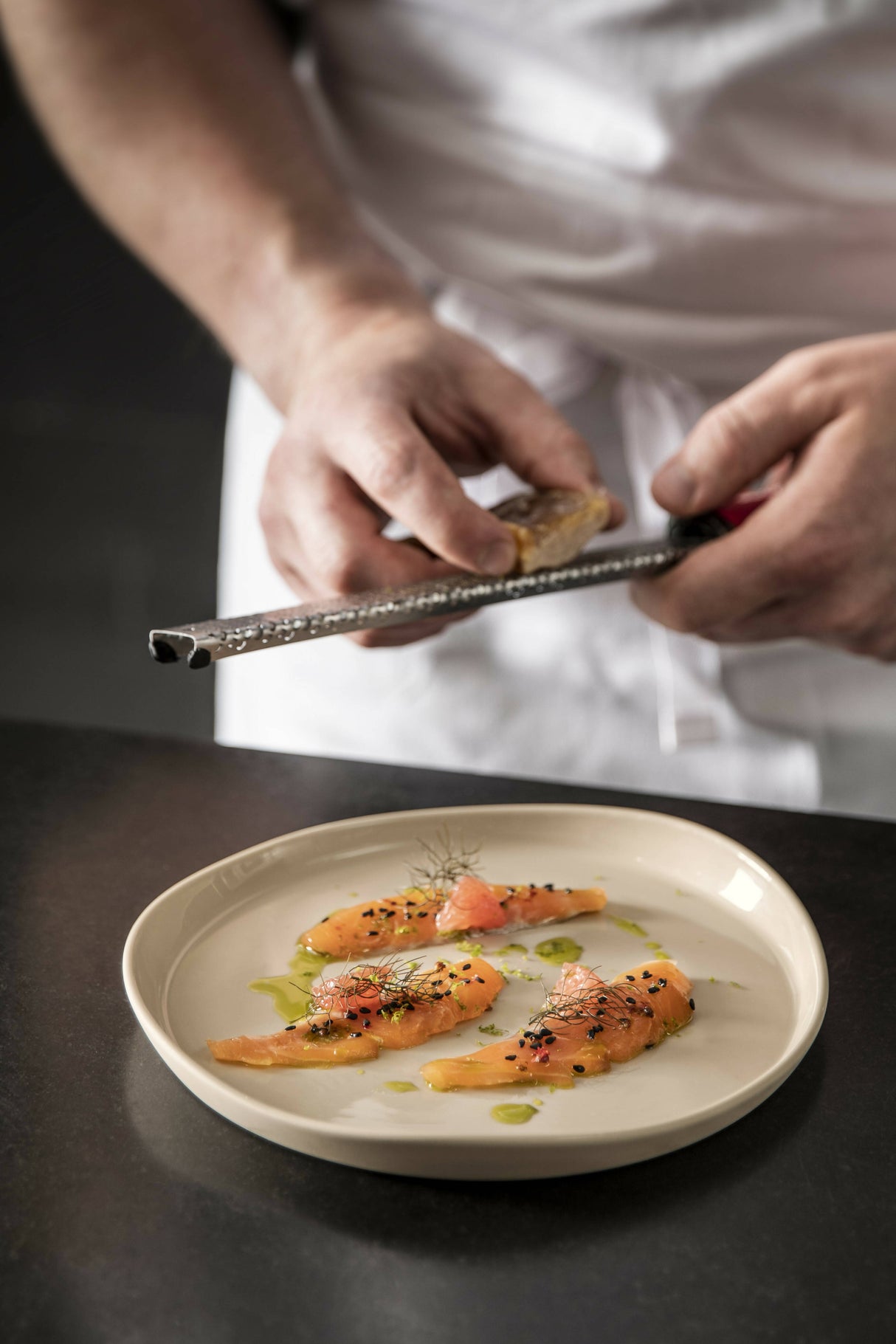 A chef serving a high end fish dish in a Degrenne Paris Beige plate