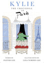 Book cover for 'Kylie the Crocodile in Paris' featuring an illustrated green crocodile wearing a red beret sitting on a Parisian balcony with the Eiffel Tower visible in the window, on a white brick-patterned background.